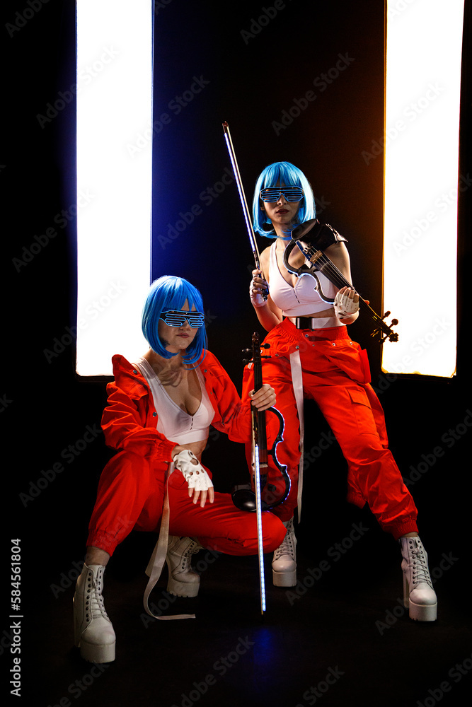 Obraz premium Violinist women in the cyberpunk costumes on the black background.