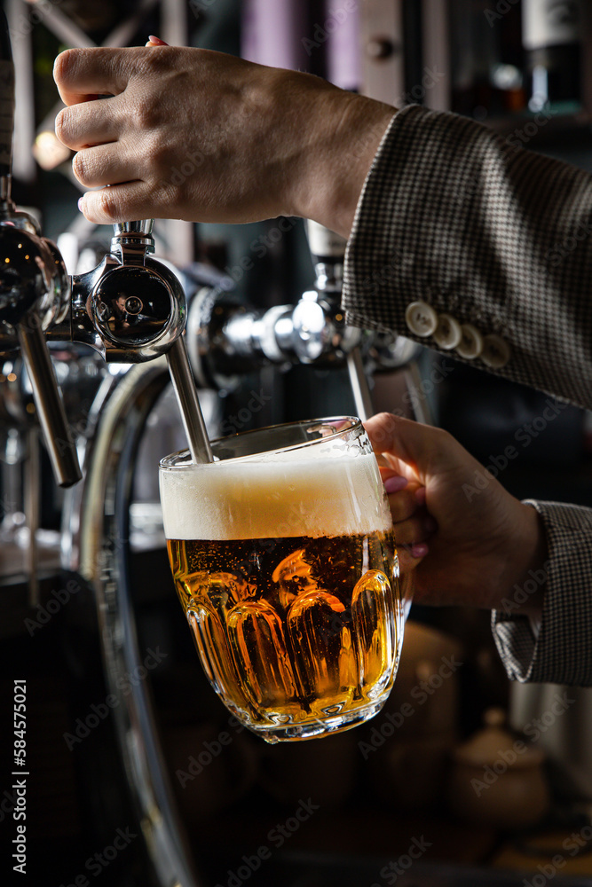 A bartender pours a glass of beer in a bar.