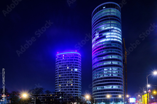 High-rise buildings captured with long exposure. Two illuminated skyscrapers in the evening