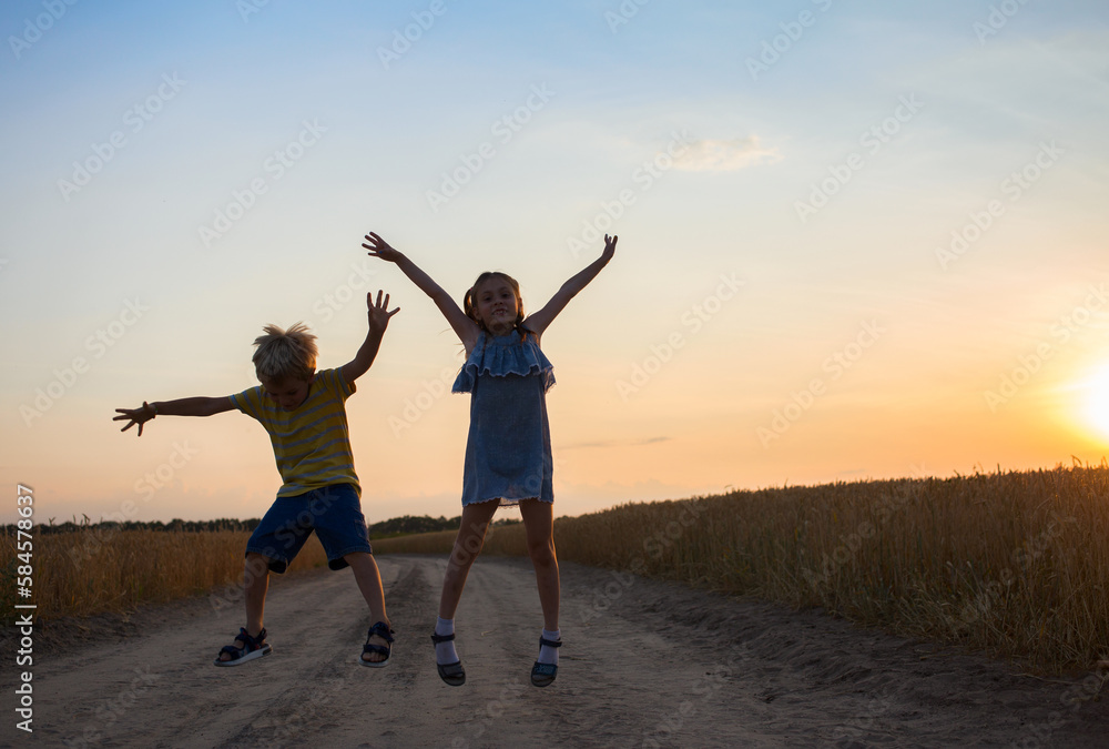 Silhouettes of cheerful girls and boys jumping for joy against the backdrop of the sunset sky. fun, excitement. childhood, summer walks, friendship