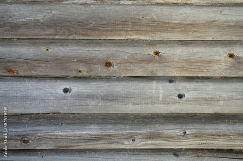 A wooden wall made of gray-brown processed logs as a background close-up.