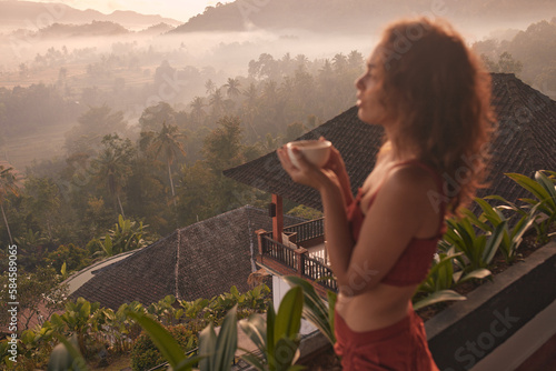 Woman enjoys a relaxing yoga retreat at a beautiful Bali resort with stunning views of the sunrise and Agung volcano. Travel and wellness concept.