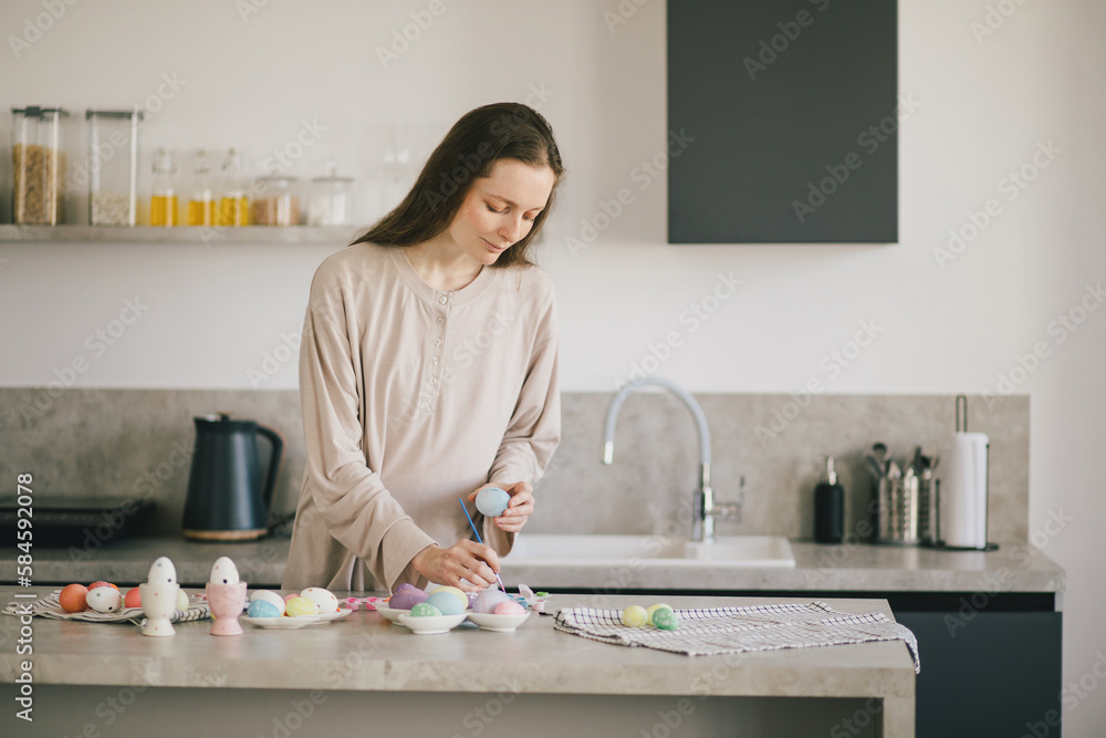 Young woman decorating Easter eggs using brush and paint on the kitchen. Young woman decorating Easter eggs using brush and paint on the kitchen.