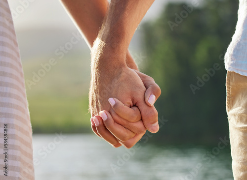Photos Holding hands, love and couple at lake outdoors for commitment, trust and support