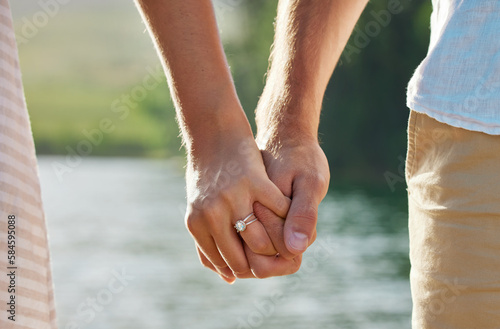 Holding hands, engagement and couple at lake outdoors for love, trust and support. Commitment, care and ring jewelry of woman and man together for romance, bonding or affection with soulmate at creek
