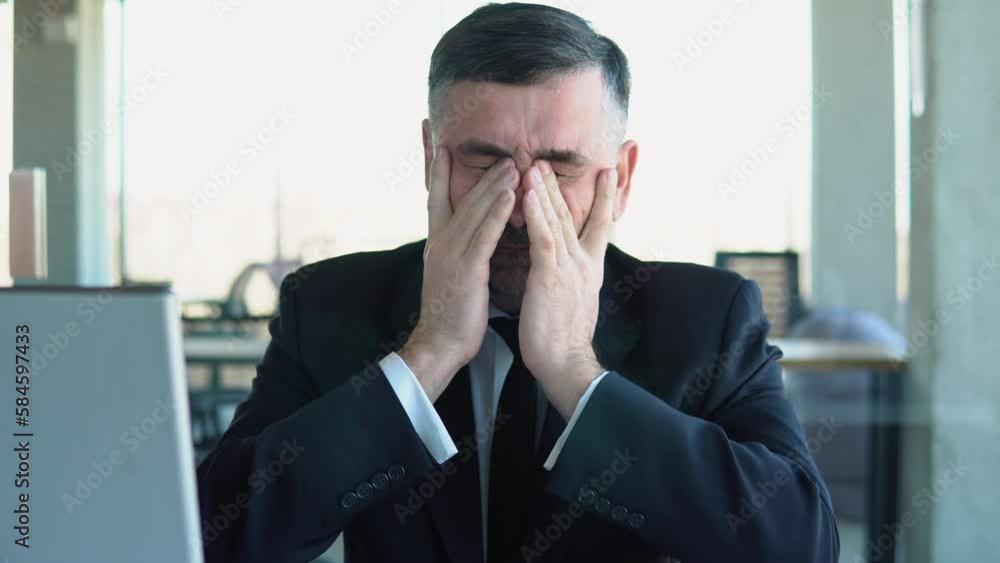 Old tired employee overwhelmed with tasks in office. Depressed senior businessman sitting at computer Old tired employee overwhelmed with tasks in office. Depressed senior businessman sitting at computer