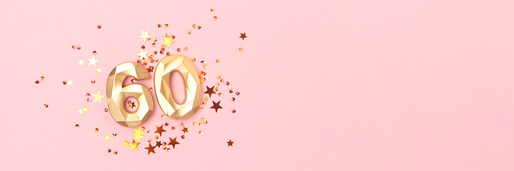 Banner with gold colored number sixty and stars confetti on a pink background. Creative concept with copy space.