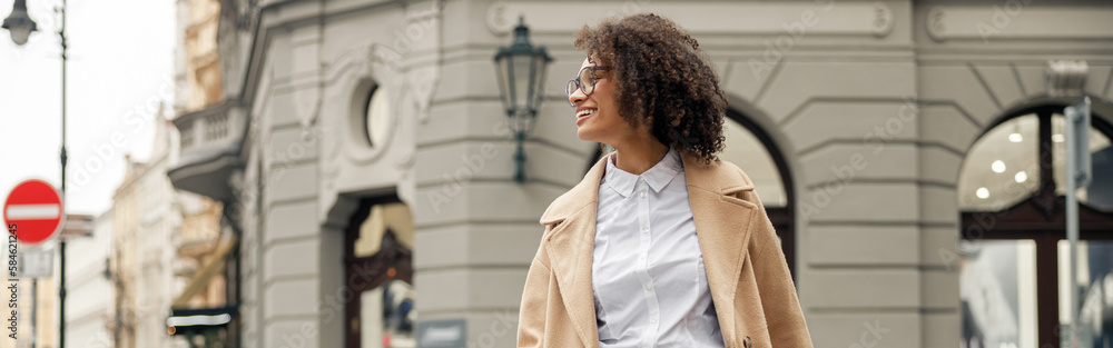 Happy woman after shopping with paper bags crosses road in city and looking at side Happy woman after shopping with paper bags crosses road in city and looking at side