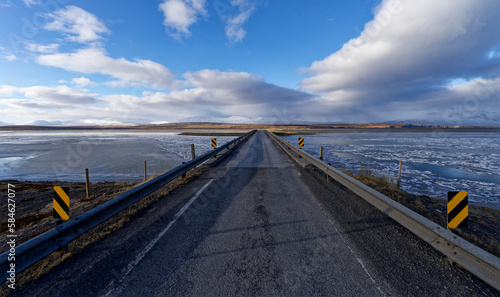 Pont de  bitume et de gravier traversant un fjord en Islande recouvert  par la glace et la neige  © pj69