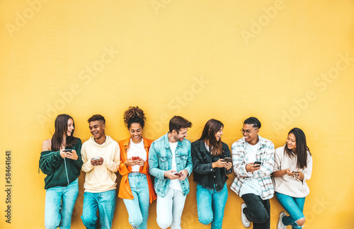 Group of young people using smart mobile phone device outside - Teenagers addicted to social media - College students watching smartphone in university campus - Modern technology concept
