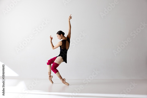 Photo of gorgeous ballerina wearing pointe shoes dancing on fingertips over white background