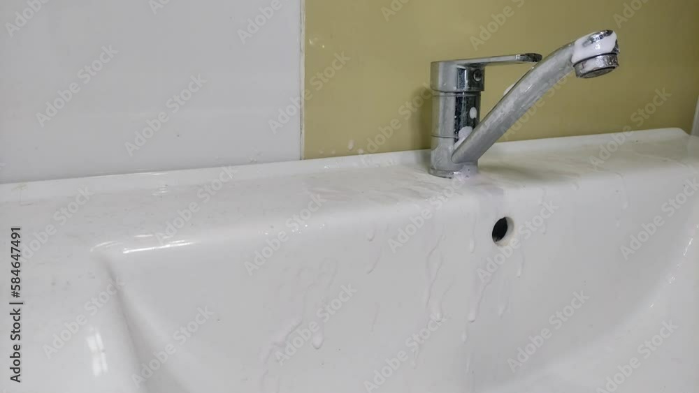 Housekeeper cleaning bathroom faucet with lime scale cleaner Housekeeper cleaning bathroom faucet with lime scale cleaner