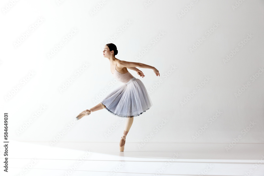 Ballerina dancing graceful movement in dress over white background. Beauty of classic ballet
