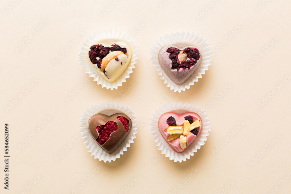 chocolate sweets in the form of a heart with fruits and nuts on a colored background. top view with space for text, holiday concept chocolate sweets in the form of a heart with fruits and nuts on a colored background. top view with space for text, holiday concept