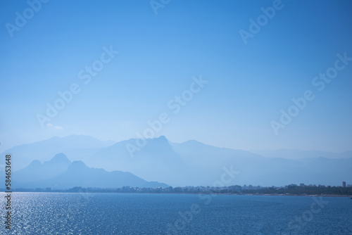 Calm sea against backdrop foggy mountains and blue sky, travel concept of beautiful places in turkey