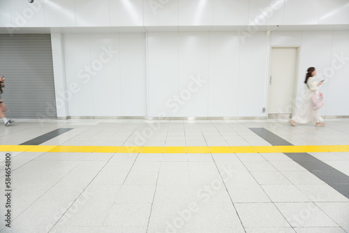 新宿駅内の白い通路を女性が歩いている背景