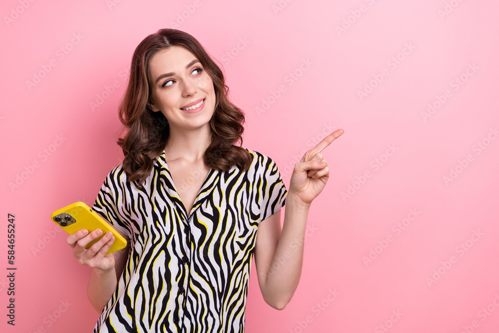 Photo of young girl wear blouse hold samsung phone direct finger look empty space fast speed internet connection isolated on pink color background Photo of young girl wear blouse hold samsung phone direct finger look empty space fast speed internet connection isolated on pink color background