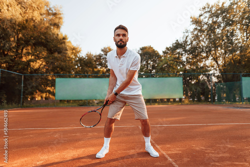 Active training. Young man is on the tennis court at sunny daytime © standret