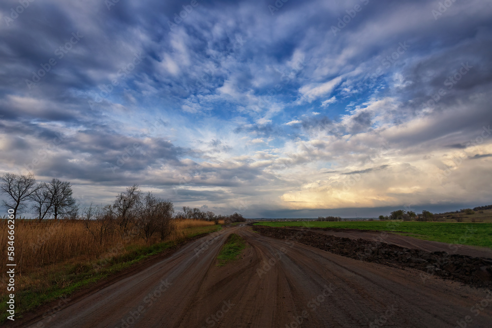 Spring country road after rain, countryside. Clouds and sky