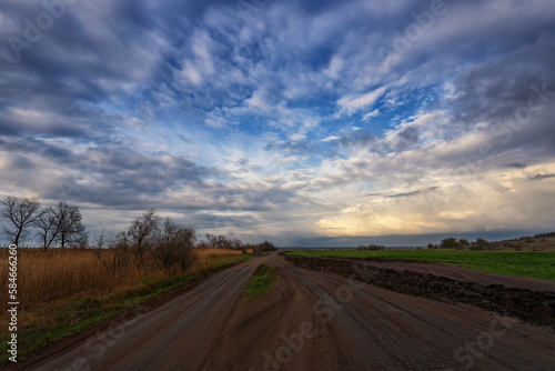Spring country road after rain, countryside. Clouds and sky