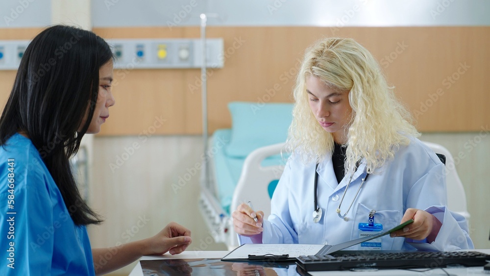 Woman medical work writes prescription on table in hospital. Patient sitting in treatment room at hospital Woman medical work writes prescription on table in hospital. Patient sitting in treatment room at hospital