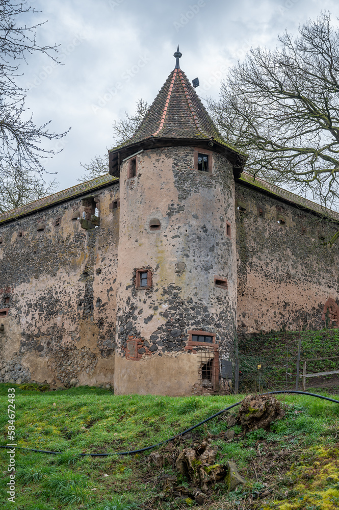 Fototapeta premium Old walls of Ronneburg Castle with a round tower and meadow in front during cloudy day, Germany, vertical shot