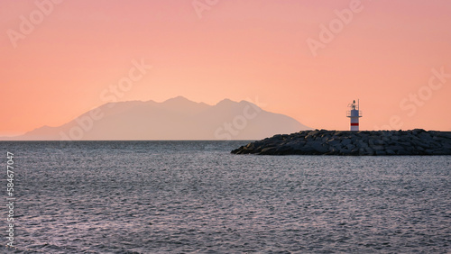 Two lighthouses facing each other in the port of Gokceada Imbros island at sunset with clear orange sky . Çanakkale Turkiye