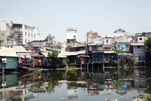 Old houses on stilts in the slums of Saigon along a river full of trash. Poor residential area in Ho Chi Minh City, Vietnam, standing on water