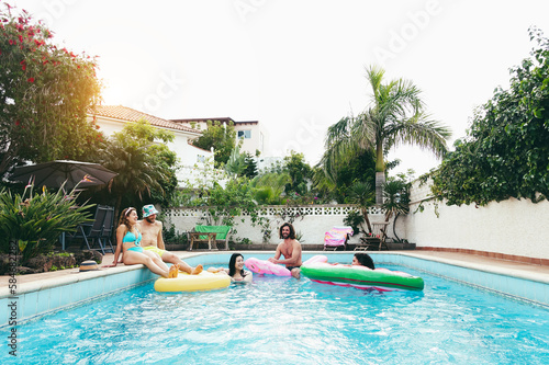 Happy people having fun inside swimming pool - Main focus on left girl face - Summer  party and travel concept