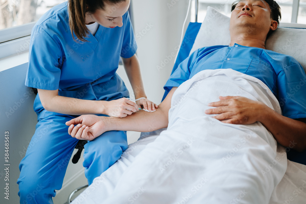 Friendly Female Head Nurse Making Rounds does Checkup on Patient Resting in Bed. She Checks tablet while Man Fully Recovering after Successful Surgery in hospital. Friendly Female Head Nurse Making Rounds does Checkup on Patient Resting in Bed. She Checks tablet while Man Fully Recovering after Successful Surgery in hospital.
