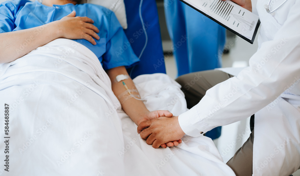 Female doctor holding male patient hand on the bed with receiving saline solution in hospital . Female doctor holding male patient hand on the bed with receiving saline solution in hospital .