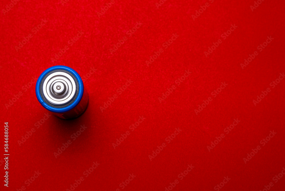 A thick round battery on a red background. A thick round battery on a red background.