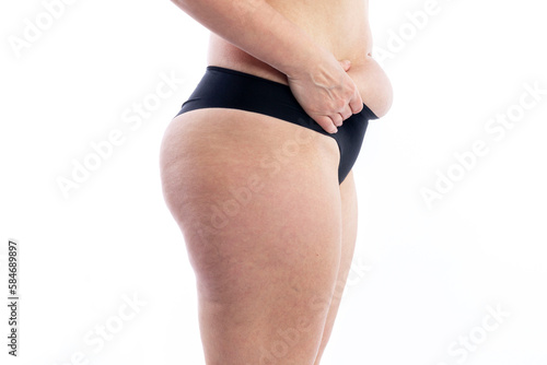 Female body in black shorts with overweight and cellulite keeps belly fat. Close-up. Isolated on white background. Side view.