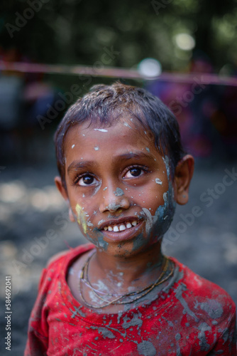 South asian hindu religious little boy enjoying holi festival,the occasion of colour , abir or gulal on face in bijoya dashami of durga puja photo