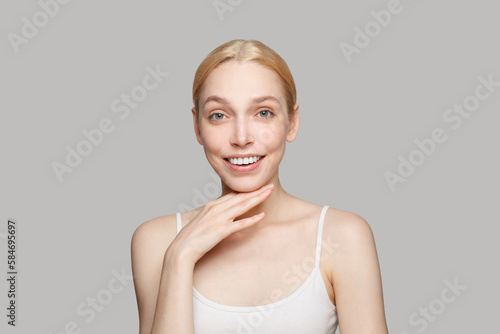 Portrait of pretty woman touching her chin and smiling isolated on grey background. Beauty, cosmetics, skincare, glamour photo