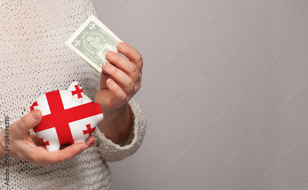 Flag of Georgia on money bank in Georgian woman hands. Dotations, pension fund, poverty, wealth, retirement concept Flag of Georgia on money bank in Georgian woman hands. Dotations, pension fund, poverty, wealth, retirement concept