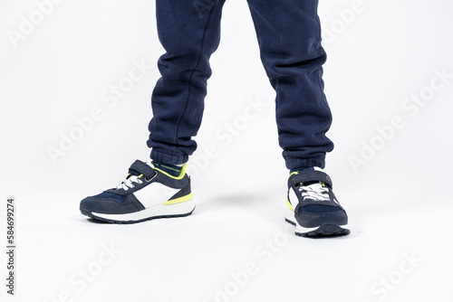 Childrens shoes. Blue kids running shoes sneakers on the legs of a five- or six-year-old boy on a white background.