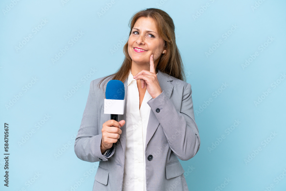 Middle-aged TV presenter woman over isolated blue background thinking an idea while looking up Middle-aged TV presenter woman over isolated blue background thinking an idea while looking up
