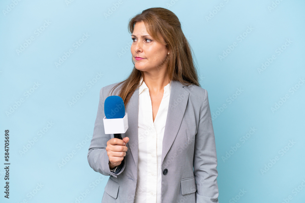 Middle-aged TV presenter woman over isolated blue background looking to the side Middle-aged TV presenter woman over isolated blue background looking to the side