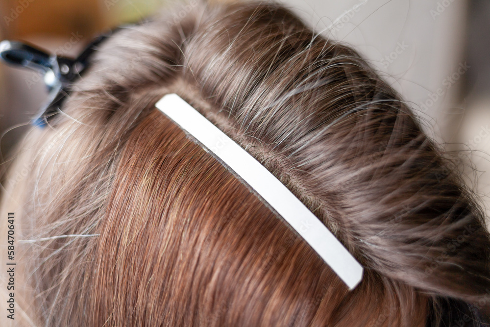 Obraz premium Hair ribbons for extensions on a woman's head at home. Hair extensions to thicken your own. Individual strands of hair close-up
