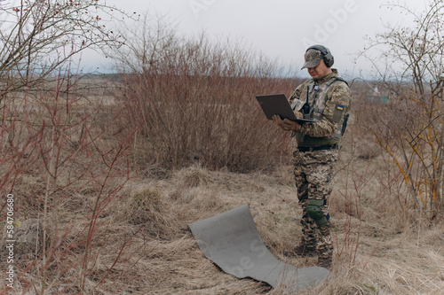 military man stands in camouflage and works with a laptop. military intelligence