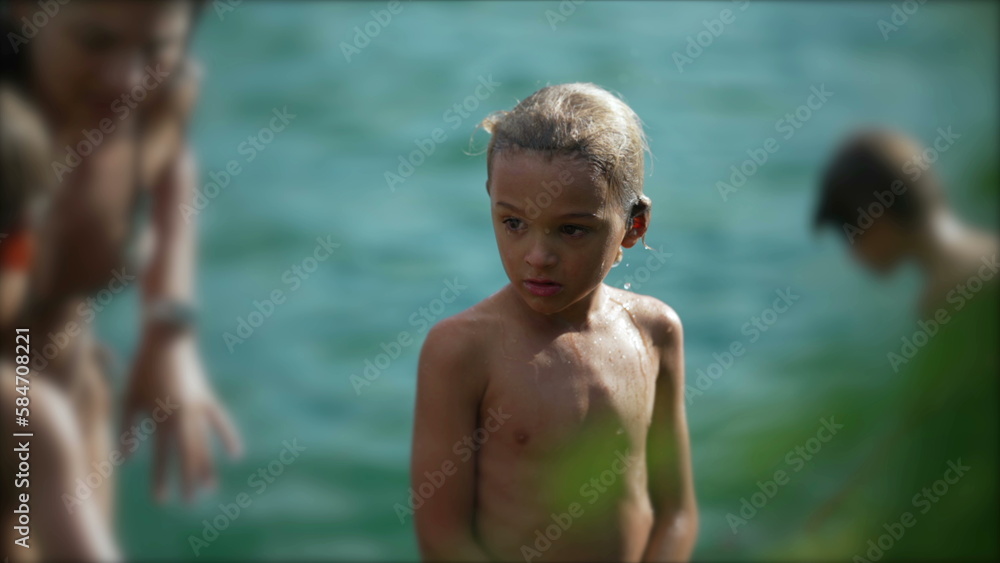 Pensive child standing outside after bathing at beach. Thoughtful small boy stands outdoors. Wet kid Pensive child standing outside after bathing at beach. Thoughtful small boy stands outdoors. Wet kid