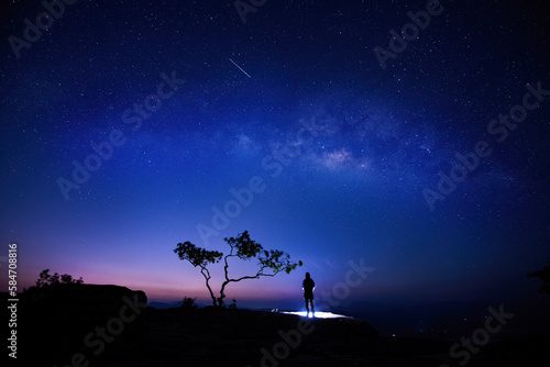 Traveler hiker who sitting top of mountain with lighting beautiful night starry sky milky way is travel and nature holidays concept.