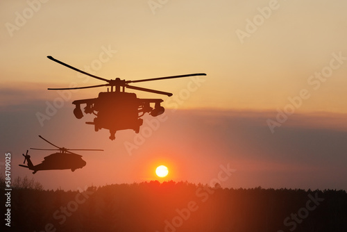Silhouettes of helicopters on background of sunset.