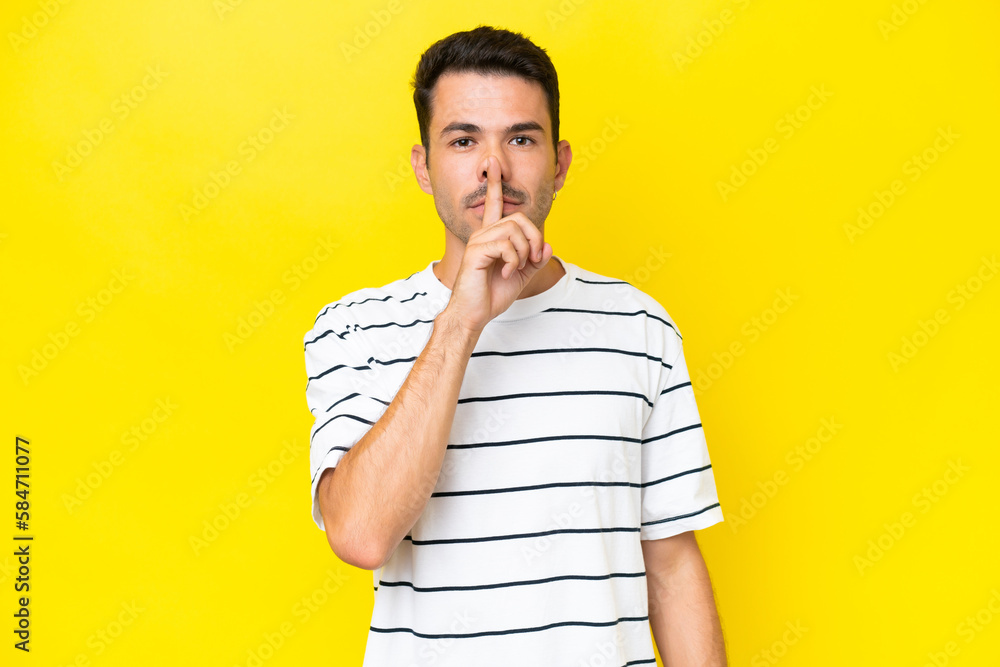 Young handsome man over isolated yellow background showing a sign of silence gesture putting finger in mouth Young handsome man over isolated yellow background showing a sign of silence gesture putting finger in mouth
