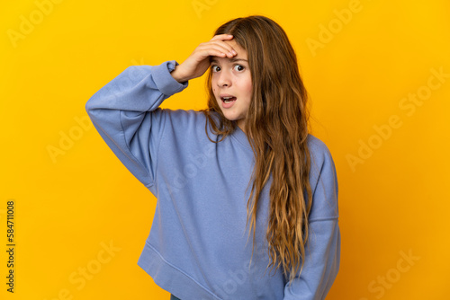 Child over isolated yellow background doing surprise gesture while looking to the side