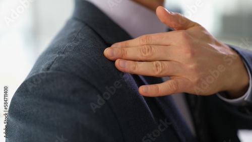 Businessman in business suit brushing off dust or dandruff from his shoulder closeup
