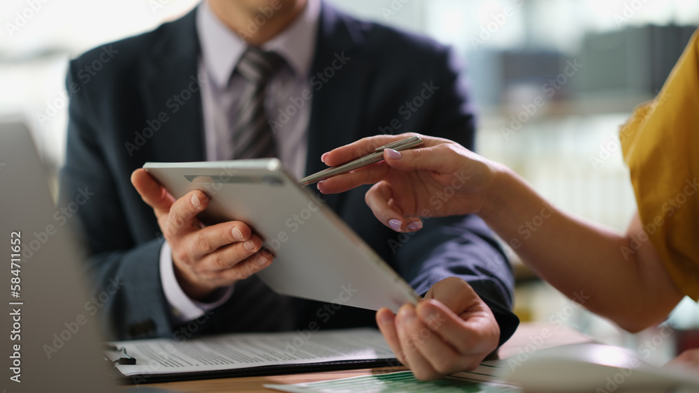 © H_Ko - Business partners discussing information on tablet and showing screen with pen closeup