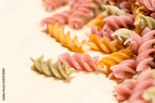 Rice vegetable pasta in the form of spirals on a white background. Healthy rice pasta with tomatoes  selenera  carrots and beets