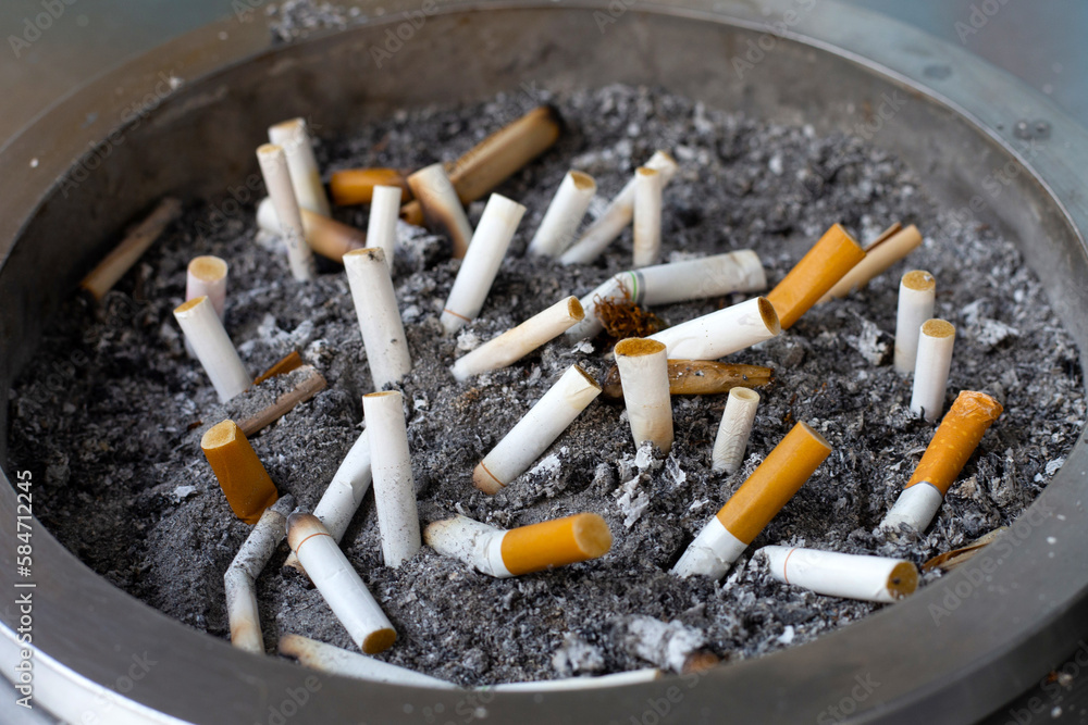 Cigarettes and ash on dirty sand in trash tray Cigarettes and ash on dirty sand in trash tray